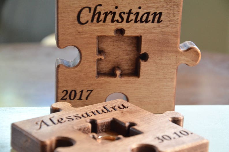 May include: Two wooden puzzle pieces with the names "Christian" and "Alessandra" engraved on them. The pieces are joined together and have the date "2017 30.10" engraved on them.