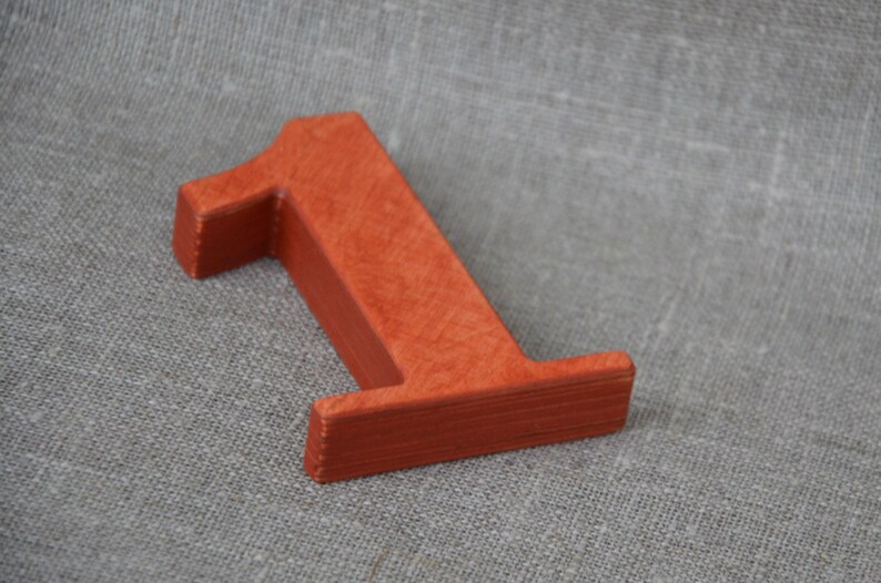 Op de afbeelding: Een houten nummer &eacute;&eacute;n, geverfd in een heldere oranje-rode kleur. Het nummer is gemaakt van massief hout en heeft een glad, licht getextureerd oppervlak.