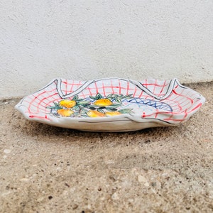 May include: White ceramic serving dish with a red and white checkered pattern and a hand-painted design of lemons and olive branches.