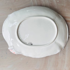 May include: White ceramic serving dish with a scalloped edge. The bottom of the dish is marked "Bordighera" and "Fatto a Mano in Italia".