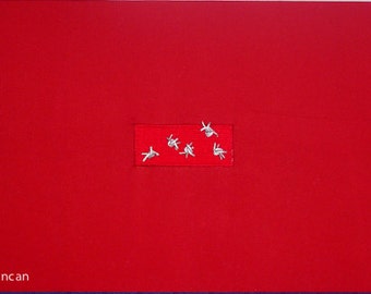 Título - "Rojo 2" Un tapiz tejido abstracto que incorpora alambre de púas en un campo de tela roja.