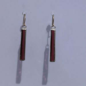 May include: A pair of dangle earrings with a gold hook and a rectangular, burgundy-coloured stone.