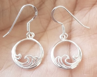 May include: A pair of silver dangle earrings with a wave design. The earrings are made of sterling silver and have a hook closure.