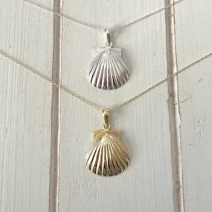 May include: Two silver necklaces with a seashell pendant. The top necklace has a silver seashell pendant and the bottom necklace has a gold seashell pendant.