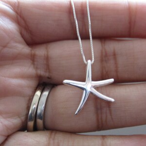 May include: A silver chain necklace with a silver starfish pendant.