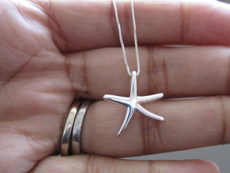 May include: A silver chain necklace with a silver starfish pendant.