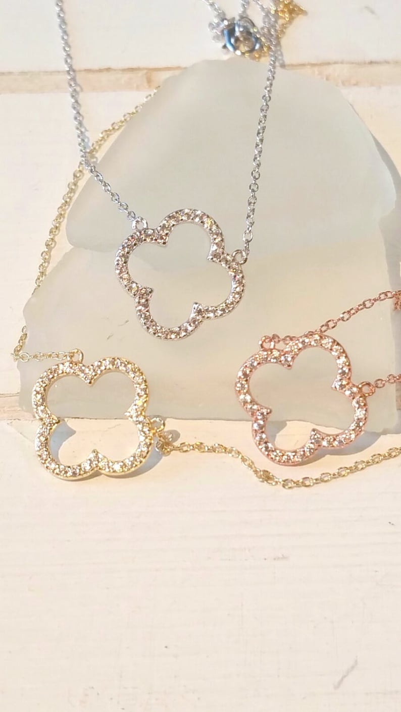 Puede incluir: Tres delicados collares con un colgante en forma de tr&eacute;bol. Cada colgante est&aacute; incrustado con peque&ntilde;as piedras brillantes. Los collares son de oro, plata y oro rosa.