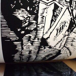 The image shows a part of the printmaking process. Linocut is a printing technique that requires carving in linoleum block. After carving you put a layer of the color and print it. This is the moment when you peel the print of the matrix.