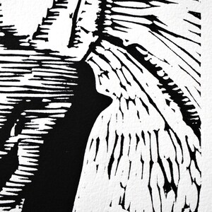 The image shows a detail of the print shot at a diagonal angle. On the left side of the image is the lower part of the building that is in shadow. On the right side of the image is a pavement with a shadow of a man riding a bicycle.