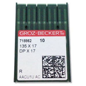 Puede incluir: Un paquete de plástico verde de 10 agujas para máquina de coser. El paquete está etiquetado con "GROZ-BECKERT" y tiene el número de producto "718862". Las agujas son de tamaño 10, 135 x 17, DP x 17. El paquete también tiene un código QR y las letras "AACU1U AC".