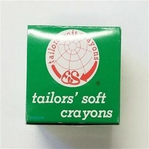 May include: A green box with the text "tailors' soft crayons" and a red and white logo with the letters "ES" inside a circle. The logo is surrounded by the text "soft crayons" and "tailors".