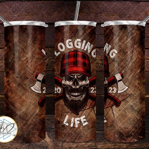 May include: A set of three stainless steel tumblers with a rustic brown background and a skull wearing a red and black plaid hat. The skull is holding two axes and the text "LOGGING LIFE" is printed on the tumbler. The years 2020, 2021, and 2023 are printed on the tumblers.