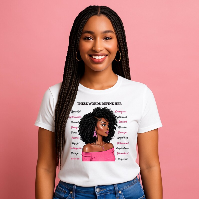May include: A white t-shirt with the text "THESE WORDS DEFINE HER" and a graphic of a woman with curly black hair and a pink top. The shirt also lists positive words like "Beautiful" and "Courageous".
