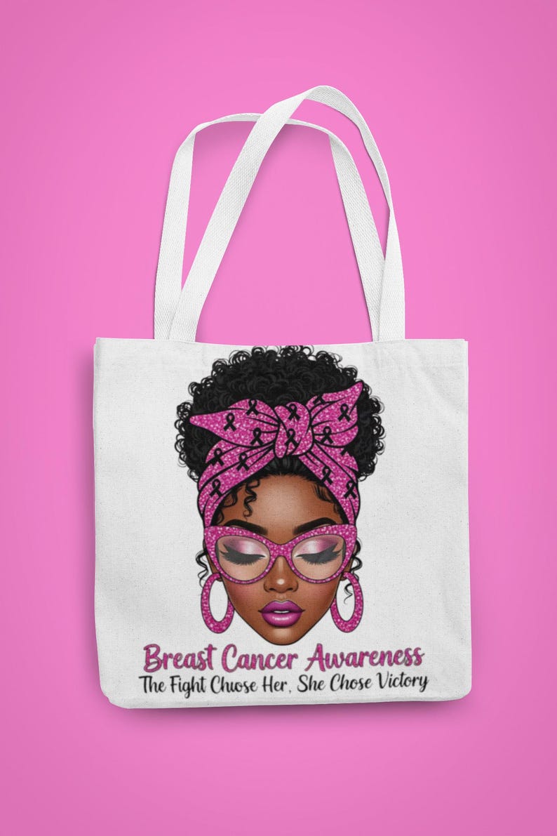 May include: White tote bag featuring a graphic of a woman with a pink headscarf and glasses, adorned with pink ribbons. The text "Breast Cancer Awareness" and "The Fight Chose Her, She Chose Victory" are below the image. The bag has white handles.