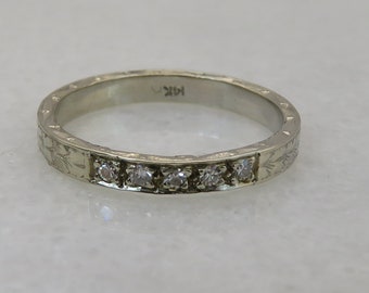 May include: A thin silver band with a delicate floral design and five small diamonds set in a row.