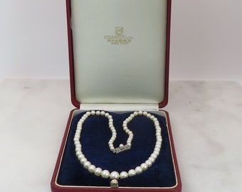 May include: A white pearl necklace with a silver clasp in a red velvet jewelry box. The box has a white interior and the text "Authentic Pearls, Inc. New York, New York" printed on the inside of the lid.