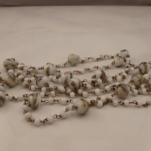 May include: A long white glass bead necklace with colorful swirls and copper chain links.
