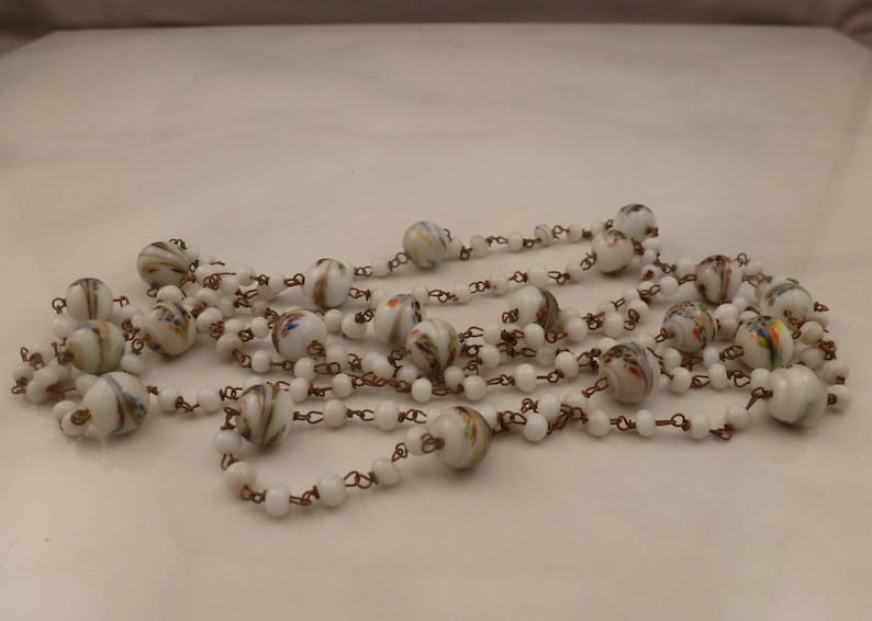 May include: A long white glass bead necklace with colorful swirls and copper chain links.