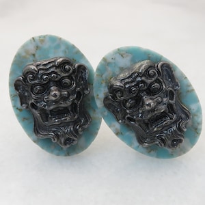May include: A pair of blue and white ceramic earrings with a silver lion head design.