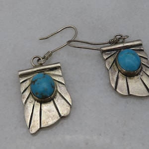 May include: A pair of silver earrings with turquoise stones set in a fan-shaped design.