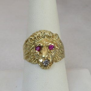 May include: A gold lion head ring with ruby eyes and a single diamond in the mouth.