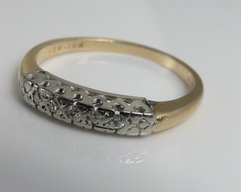 May include: A delicate gold and silver ring with a row of small diamonds set in a filigree design.