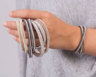 May include: A set of six leather bracelets with crystal embellishments. The bracelets are in shades of gray, beige, and brown.