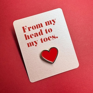 May include: A white card with the text "From my head to my toes." in red lettering. A red heart-shaped pin is attached to the card.
