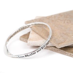 May include: A silver bangle bracelet with the inscription "We have been Mother and Son right from the start".