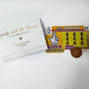 K&ouml;nnte beinhalten: Eine wei&szlig;e Geschenkkarte mit goldenem Text, der "party with the Paines, A GIFT FROM US TO YOU!" und "Chloe and Luke 18.05.25" lautet. Daneben ein Lotterieschein und eine M&uuml;nze.