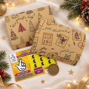 May include: Two brown kraft paper envelopes with Christmas tree and postage stamp patterns, featuring the text "have yourself a lucky" and "a little christmas luck just for you". A National Lottery scratch card and a two-pound coin are included.