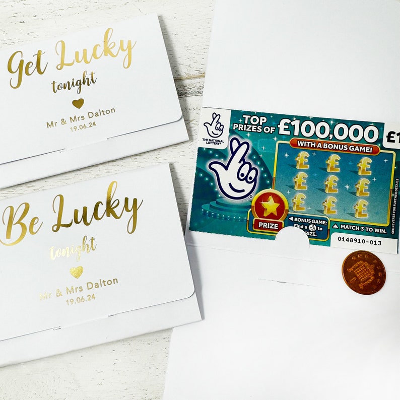 May include: Two white envelopes with gold foil lettering that reads "Get Lucky tonight" and "Be Lucky tonight". The envelopes are personalized with the names "Mr & Mrs Dalton" and the date "19.06.24". A scratch-off lottery ticket is visible in the background.