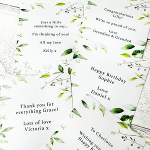 Puede incluir: Un conjunto de tarjetas de felicitaci&oacute;n blancas con bordes florales verdes y blancos. Cada tarjeta presenta mensajes personalizados como "Feliz Cumplea&ntilde;os Sophie" y "&iexcl;Felicidades Lilly!" con nombres y sentimientos.