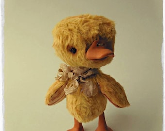 May include: A handmade yellow duck plush toy with a brown beak and a beige ribbon around its neck. The toy is fully jointed and can be posed in two positions: standing or sitting. The text "let me present to you this cute little duck handmade of german viscose Miss Eléonore full jointed and she can be in 2 positions: stand and sit MEDVEDUSKA" is written on the image.