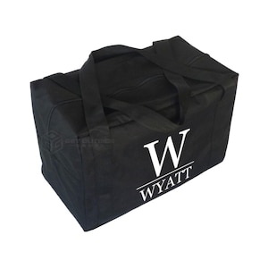 May include: A black duffel bag with two handles and a zipper closure. The bag features the name "WYATT" in white, with a large white "W" above it. The bag is rectangular and appears to be made of a durable fabric.