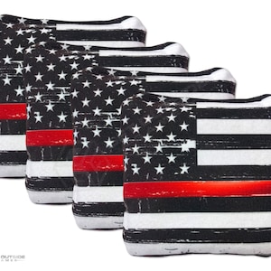 May include: Set of four bean bags featuring a distressed American flag design with a red stripe across the middle. The bean bags are perfect for cornhole or other games.