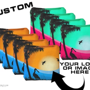 May include: Six custom cornhole bags with a sunset and palm tree design. The bags are orange, yellow, blue, and green. The bags are arranged in a row with the text 'YOUR LOGO OR IMAGE HERE' below them. The text 'CUSTOM' is in the upper left corner of the image.