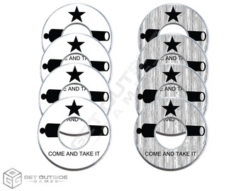 May include: A set of game pieces with a white background, featuring a black cannon, star, and the text "COME AND TAKE IT". The design is repeated on each piece, with a wood grain pattern on some.
