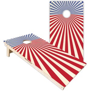 Könnte beinhalten: Zwei hölzerne Cornhole-Boards mit einem strahlenförmigen Muster aus roten, weißen und blauen Streifen. Der obere Bereich jedes Boards zeigt ein blaues Feld mit weißen Sternen, die von einem kreisförmigen Loch ausgehen und in Streifen übergehen.