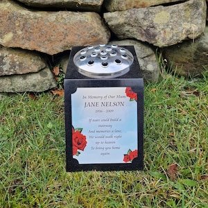 May include: Black granite memorial with a silver flower vase and a poem in memory of Jane Nelson. The poem reads: "In Memory of Our Mum JANE NELSON 1936-2009 If tears could build a stairway And memories a lane. We would walk right up to heaven To bring you home again."