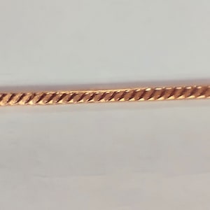 May include: A gold chain necklace with a twisted design.