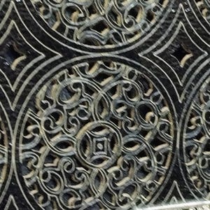 Puede incluir: Primer plano de una baldosa decorativa con un patr&oacute;n repetitivo. El dise&ntilde;o presenta formas circulares y de diamante con intrincados adornos en tonos grises y negros. La baldosa tiene un acabado brillante.