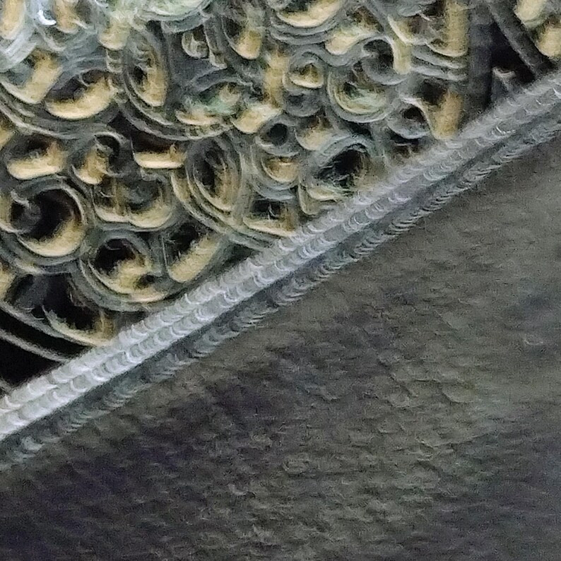 Puede incluir: Primer plano de un elemento arquitect&oacute;nico decorativo con intrincados patrones arremolinados en tonos dorados y grises. El dise&ntilde;o presenta una superficie texturizada con una l&iacute;nea diagonal de formas repetitivas detalladas.