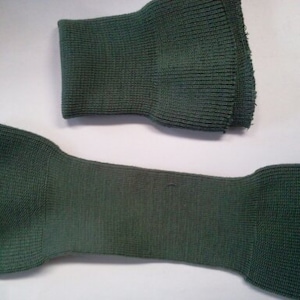 May include: Two pieces of green knitted fabric. One piece is folded in half and the other is a long strip.
