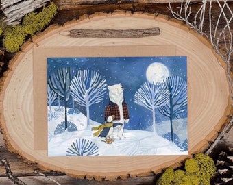May include: A greeting card depicting a winter scene. A polar bear in a red and black checked shirt stands with a penguin wearing a yellow scarf in a snowy forest under a full moon. The card is on a wooden slice with moss and a twig.