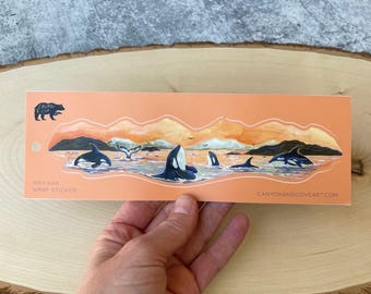 May include: A sticker featuring a pod of orcas swimming in a sunset scene with mountains in the background. The sticker is on a peach-colored background and has the text "orca pod wrap sticker" and "canyonandcoveart.com".
