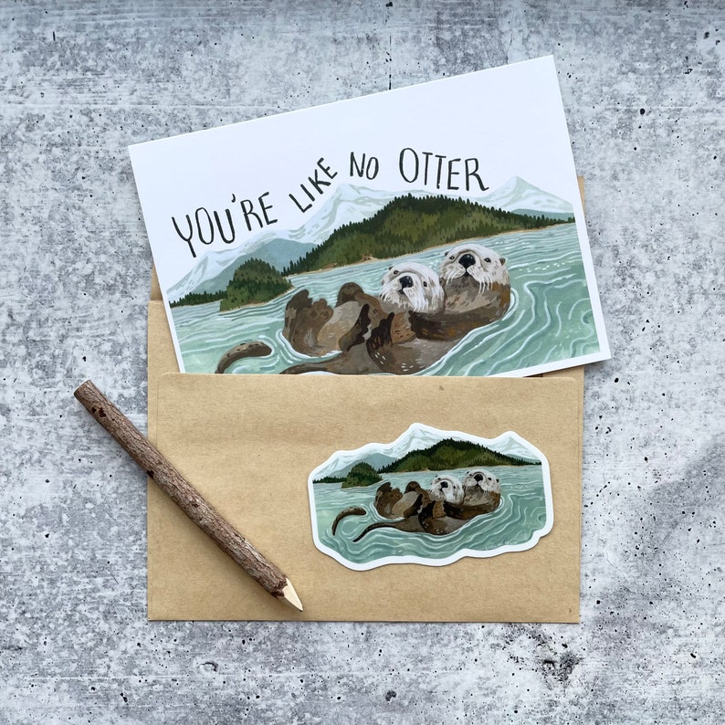 May include: A card with the text "You're like no otter" and a watercolor illustration of two otters swimming in a lake. The card is in a brown envelope with a sticker of the otters on the front.