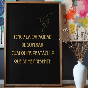 May include: A framed black print with gold text and a minimalist line drawing of a woman's face. The text reads "Tengo la capacidad de superar cualquier obstáculo que se me presente."