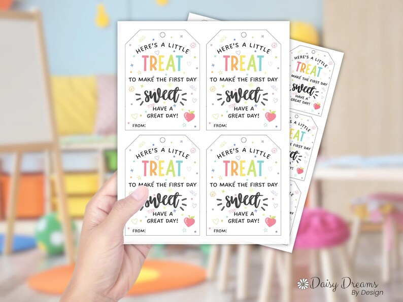 以下が含まれることがあります： 「Here's a little treat to make the first day sweet! Have a great day!」というカラフルな文字が書かれた白いギフトタグのシート。各タグにはイチゴのグラフィックと「From:」と書くスペースがあります。