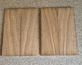 May include: Two pairs of rectangular wooden boards with a light brown color and a distinct vertical wavy grain pattern. The left pair is marked with the letter A, and the right pair is marked with the letter B, written in pencil on the wood surface.